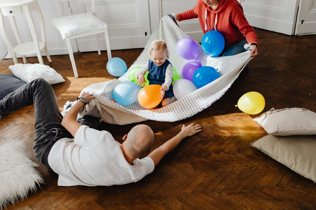 Happy family playing with colorful balloons indoors, enjoying a fun and joyful moment.