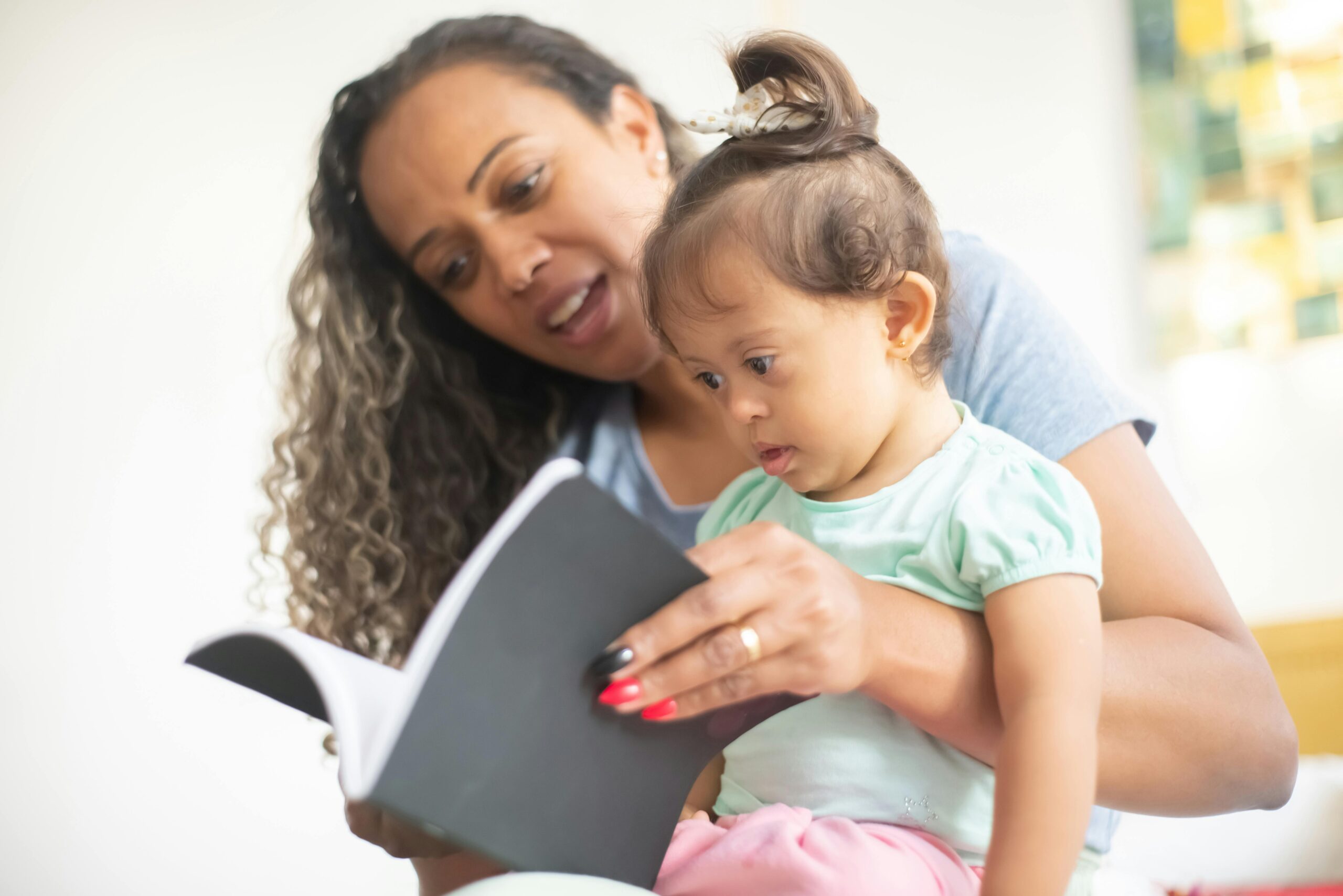 Speech Delay vs Autism: How to Tell the Difference in Toddlers A mother and her young daughter enjoy reading a book together, fostering early learning.