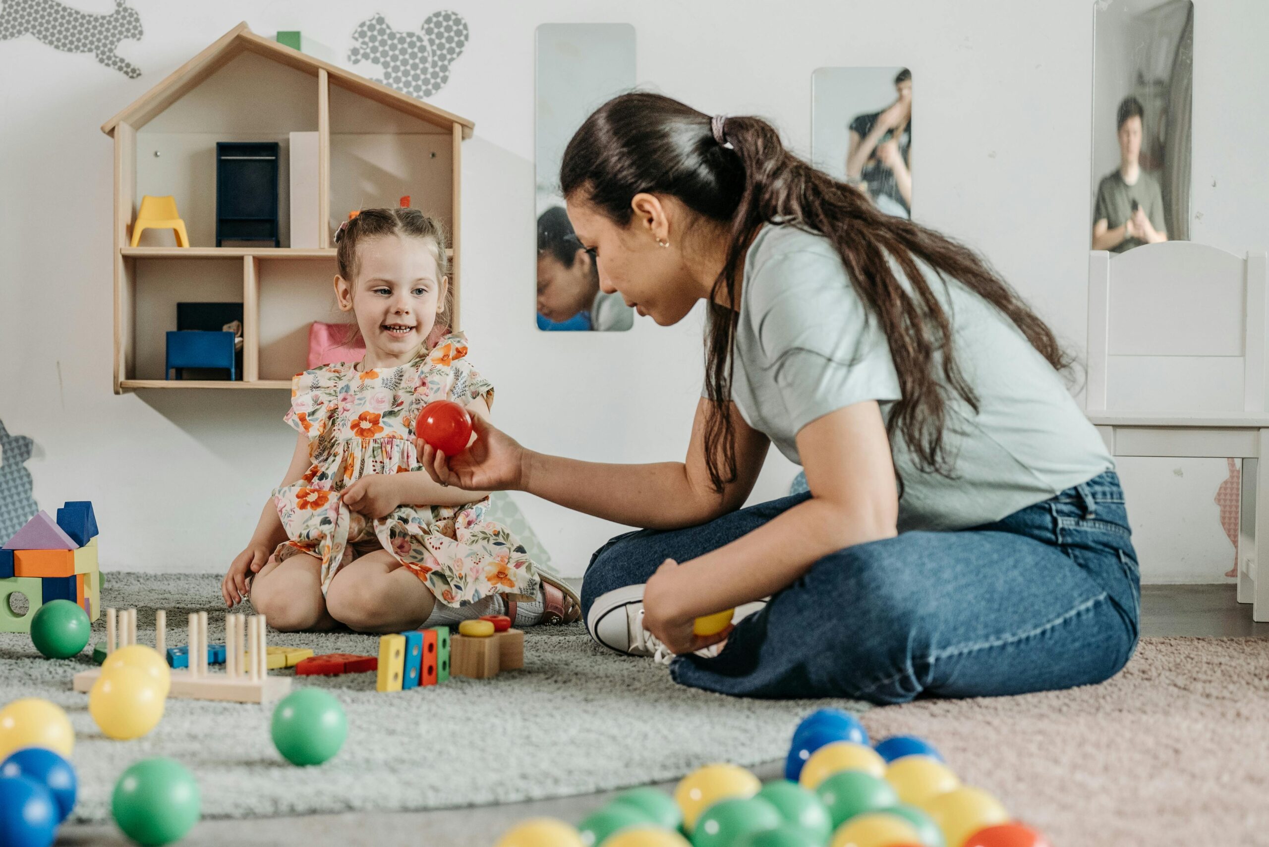 Speech Delay vs Autism: How to Tell the Difference in Toddlers A young girl and woman engaging in an educational play session in a cozy preschool setting.
