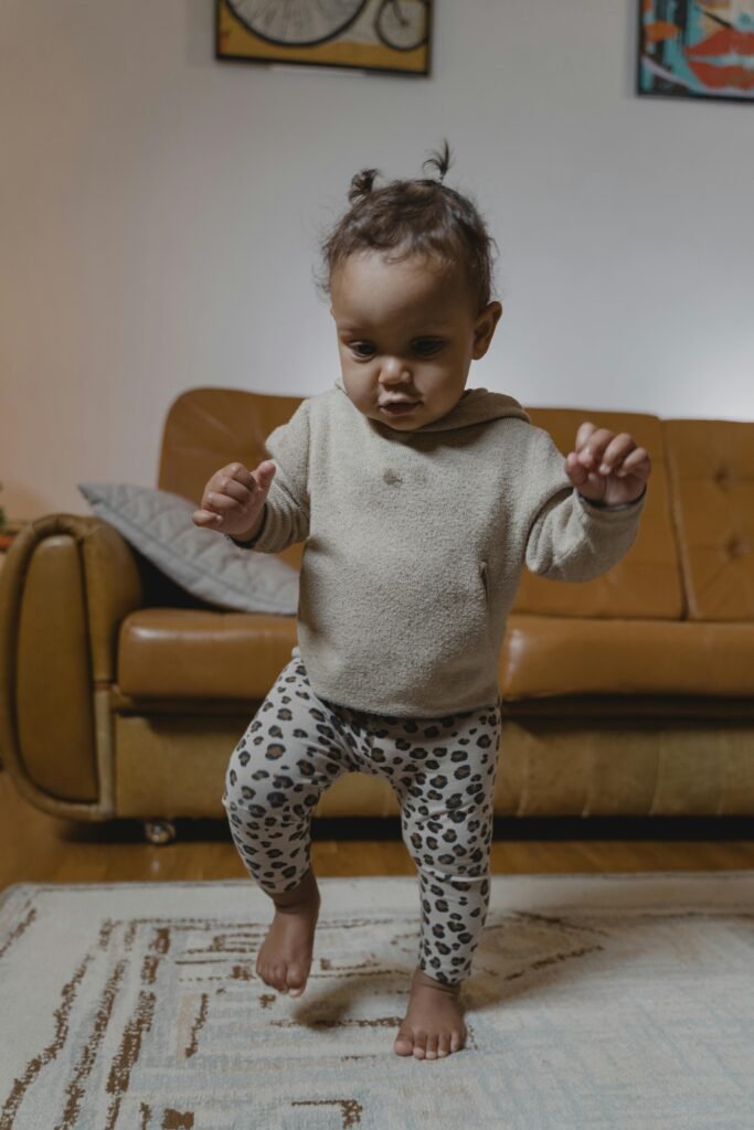 Why Some Children Walk on Their Toes: When Is It Just a Phase and When Should Parents Be Concerned? Cute baby taking first steps in a cozy, carpeted living room setting.