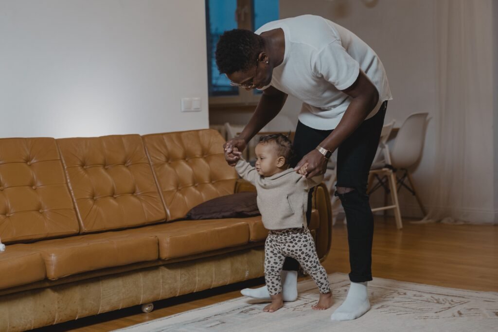 Why Some Children Walk on Their Toes: When Is It Just a Phase and When Should Parents Be Concerned? A father helps his toddler learn to walk in a cozy living room, showcasing a warm family bond.