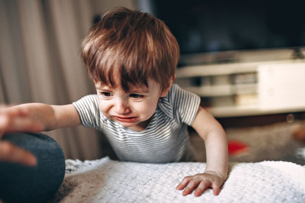 Gestures and Communication Development Crop unrecognizable parent helping unhappy child to get on comfortable sofa in light living room with modern TV in apartment
