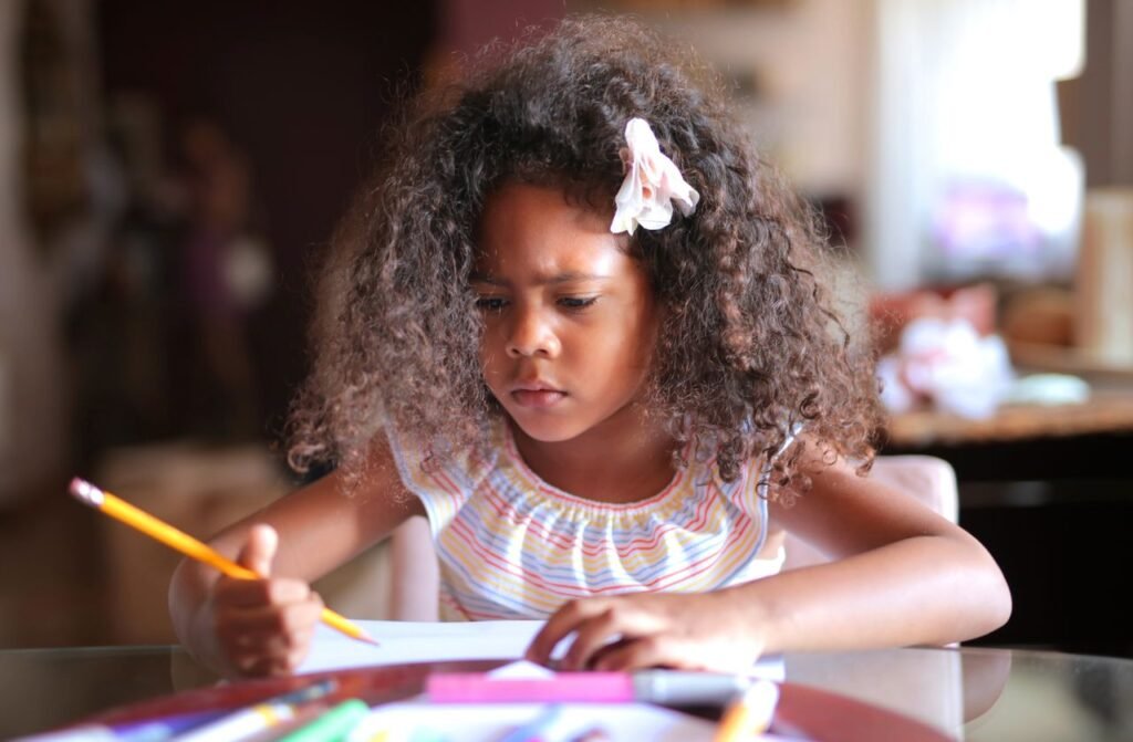 African American child focused on homework, writing with a pencil indoors.