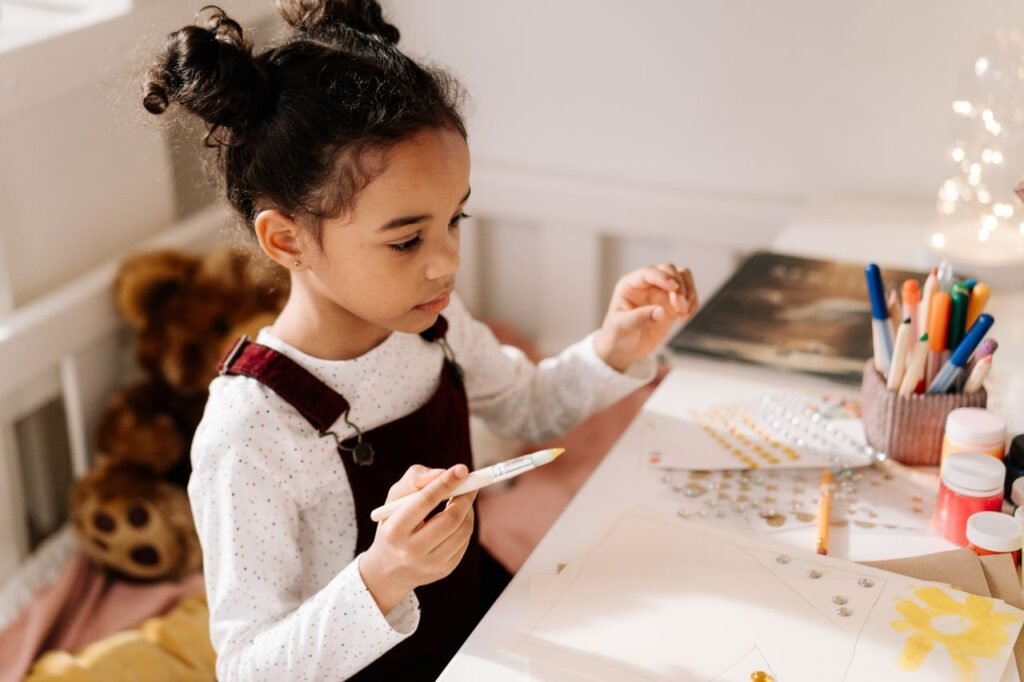 How to improve a child’s attention span A young girl enjoying a creative arts and crafts session indoors with paints and markers.