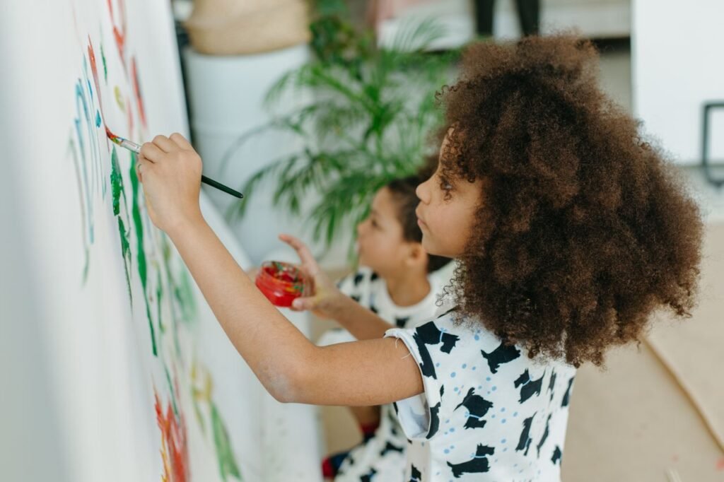 How to improve a child’s attention span Two children painting on a large white wall indoors, expressing creativity.