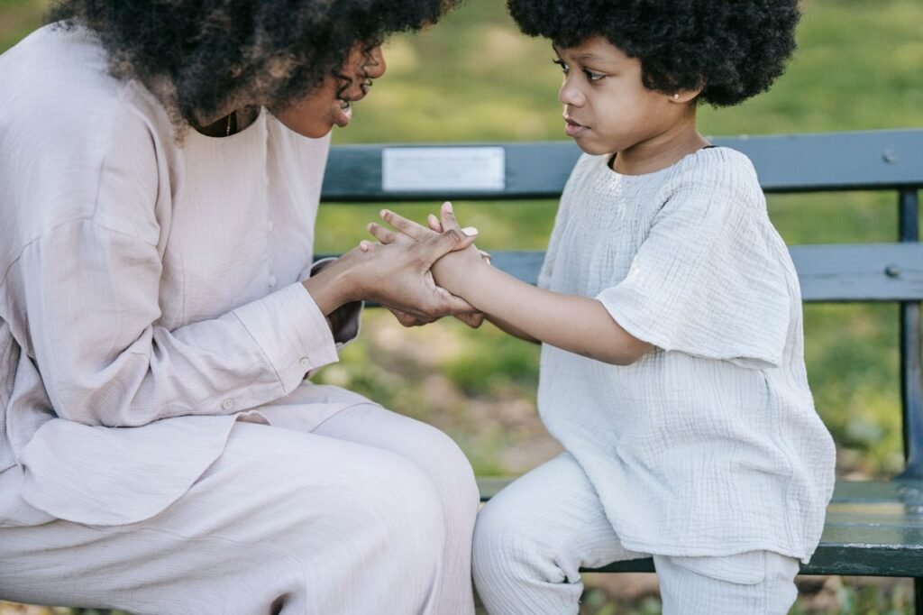 How to improve a child’s attention span A mother and child sharing a heartfelt moment of connection and affection on a park bench outdoors.