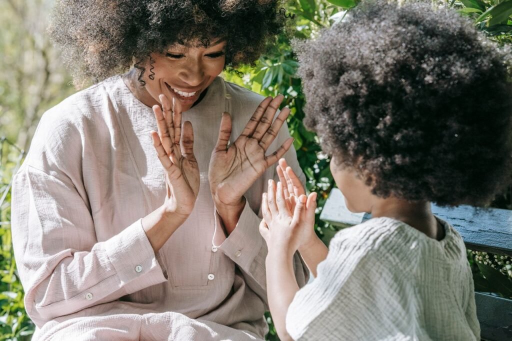 Mother and daughter share a moment playing clapping game outdoors. Vibrant and joyful interaction.
