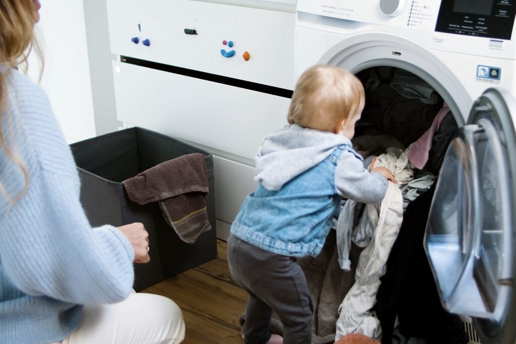 Why Parents Must Stop Doing Everything for Their Child Adorable child assisting in laundry chores indoors with mother.